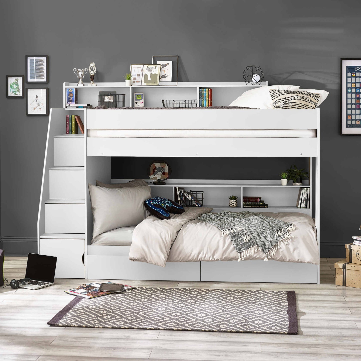 Bunk bed with side staircase in a room with a grey wall and wooden floor.