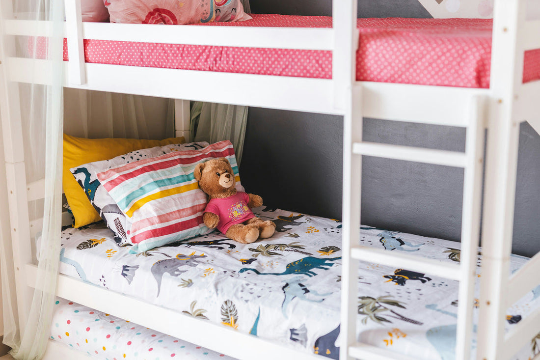 A close up of a children's bunk bed with a teddy laid next to the pillow.