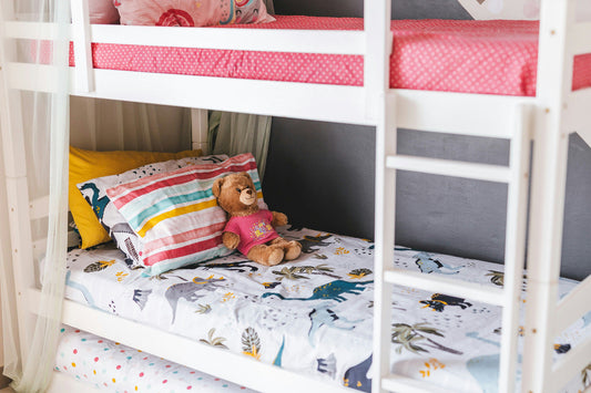 A close up of a children's bunk bed with a teddy laid next to the pillow.