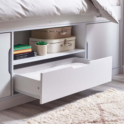 Underbed storage drawer with suitcases and books in a bedroom setting