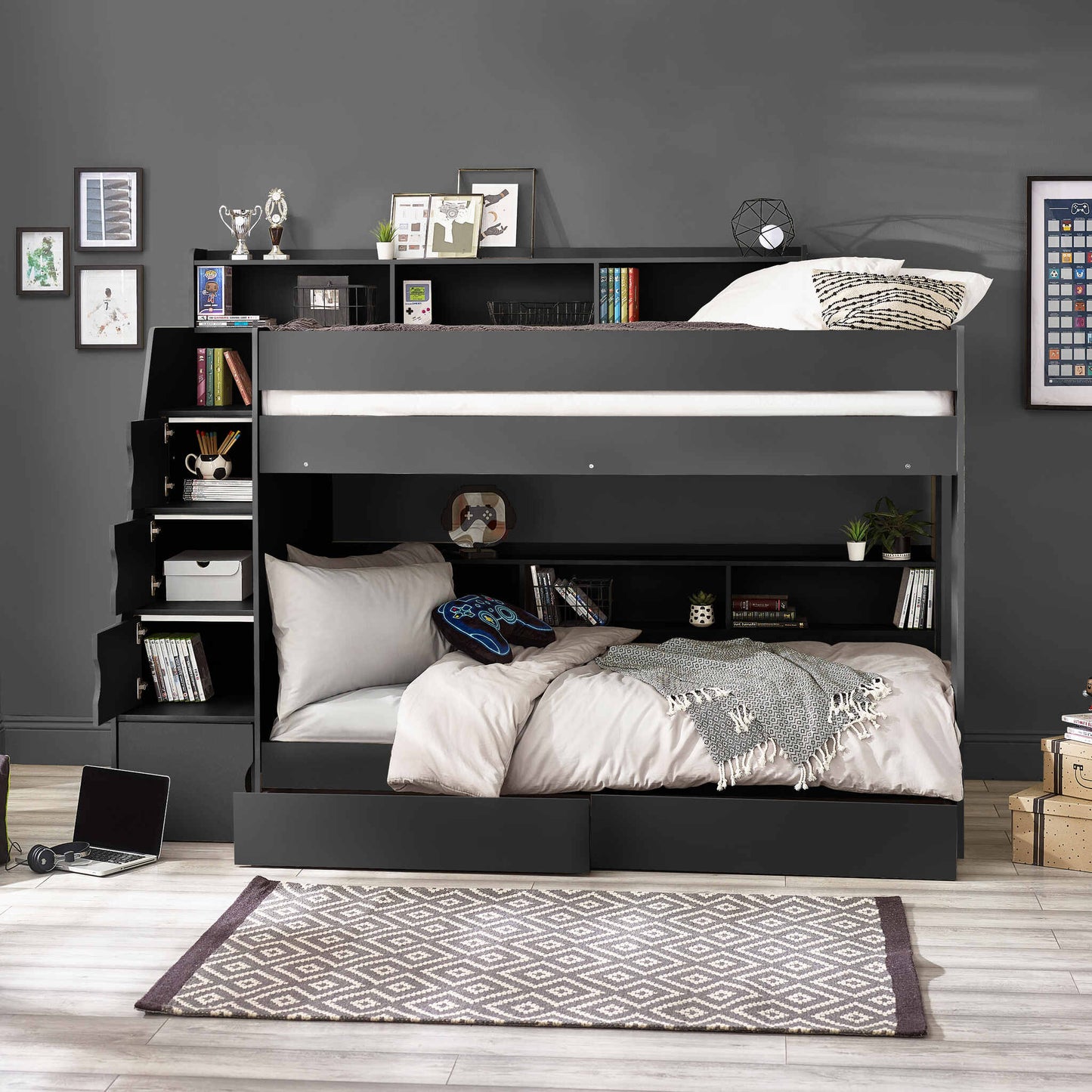 Camelot Staircase Bunk Bed in anthracite, featuring a staircase with hidden compartments and shelving. Bedroom setting with books, picture frames and a patterned rug.