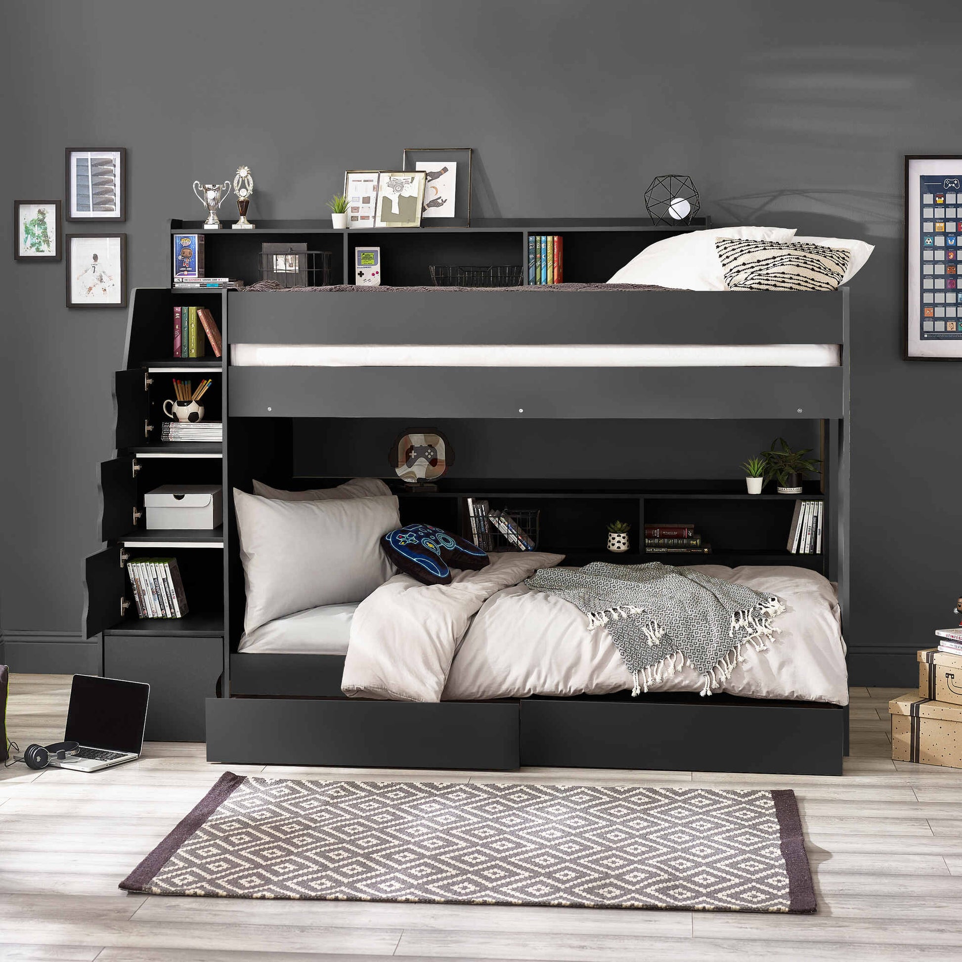 Camelot Staircase Bunk Bed in anthracite, featuring a staircase with hidden compartments and shelving. Bedroom setting with books, picture frames and a patterned rug.