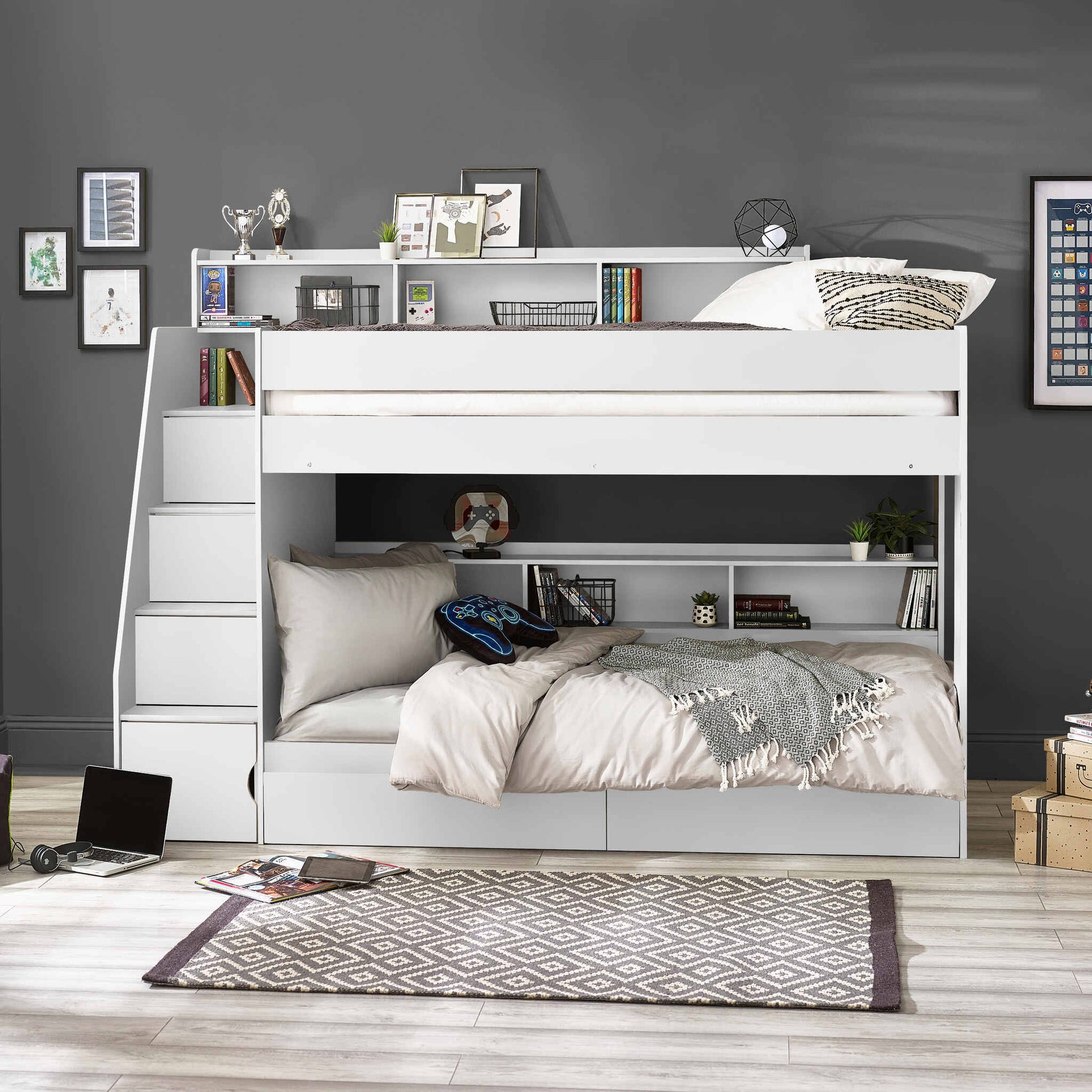 Bunk bed with side staircase in a room with a grey wall and wooden floor.